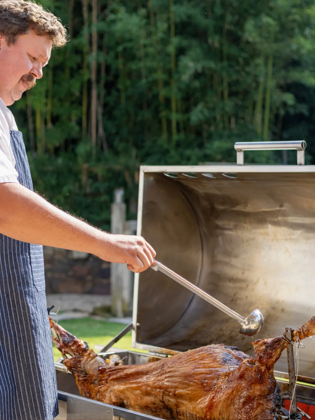 Chef basting a spit braai at a catered gathering